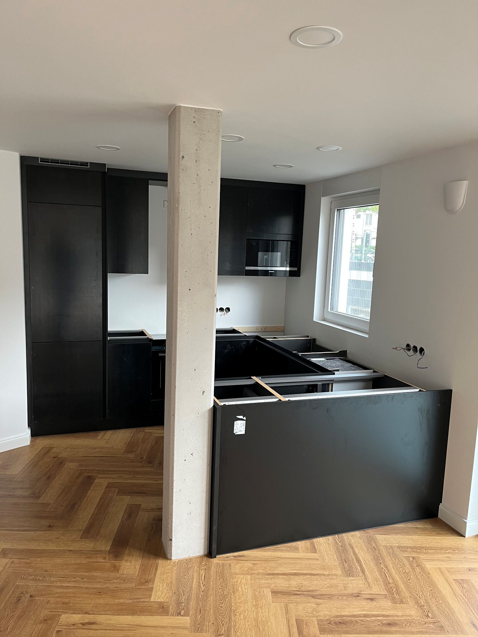 Offene Küche mit Sichtbeton-Stütze und Fischgrät-Parkett